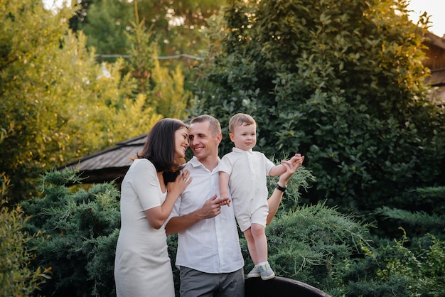 Familia feliz con su hijo caminando en el parque al atardecer. Felicidad. Amor