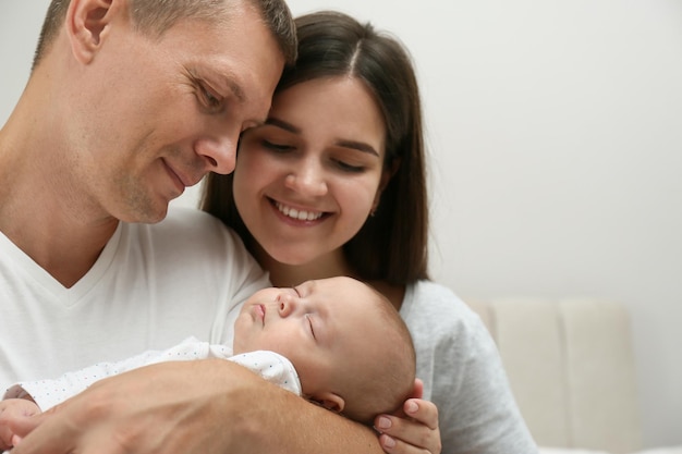 Familia feliz con su lindo bebé dormido sobre fondo gris