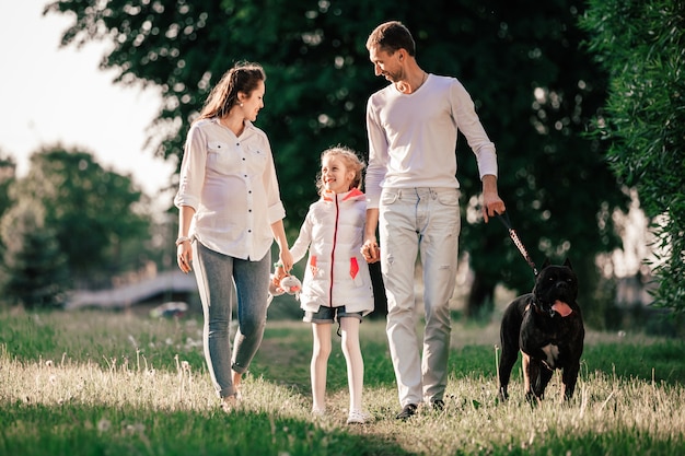 Familia feliz con su mascota a pasear por el parque.