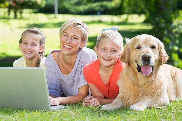 Familia feliz y su perro sonriendo a la cámara