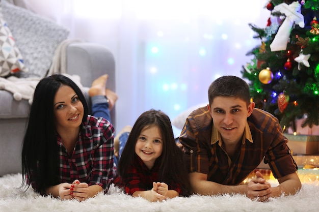 Foto familia feliz en el suelo de la sala de navidad decorada
