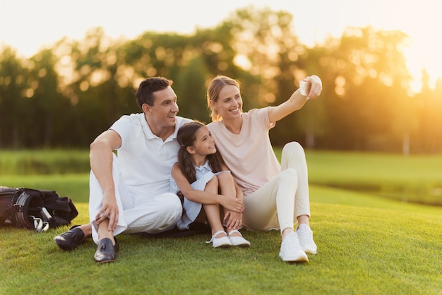 Família feliz tem descanso depois de golfe leva Selfie.