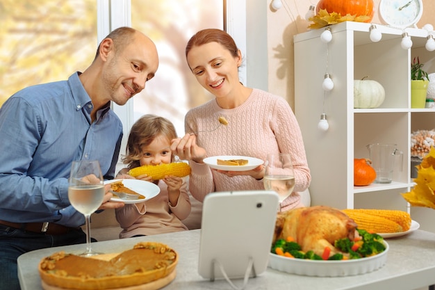 Una familia feliz tiene una cena de acción de gracias y envía un saludo en video a sus padres por Internet.