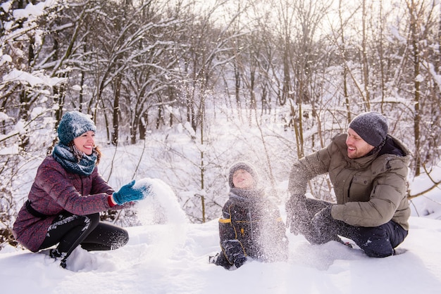 Familia feliz tirar nieve en bosque de invierno