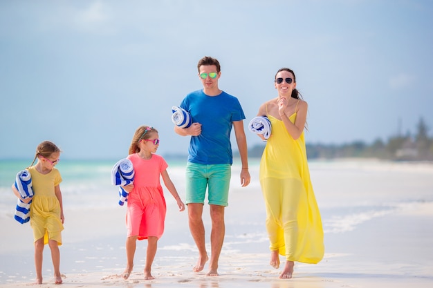 Familia feliz con toalla y disfrutando de vacaciones en una playa tropical con arena blanca y agua turquesa del océano