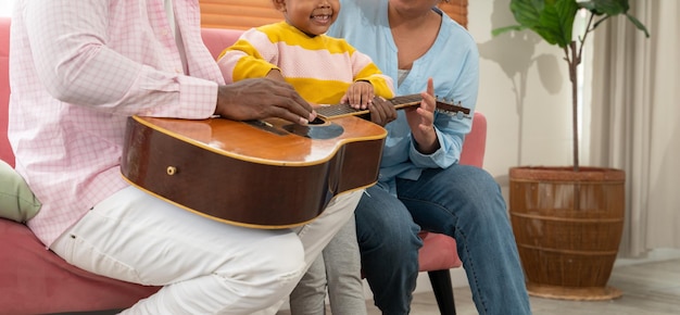 Família feliz tocando violão juntos no sofá na sala de estar em casa