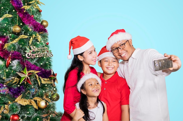 Familia feliz se toma una selfie con el árbol de Navidad