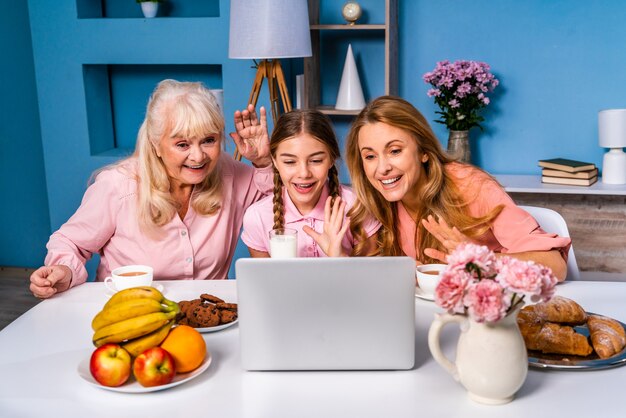 Família feliz tomando café da manhã em casa enquanto assiste a uma videochamada