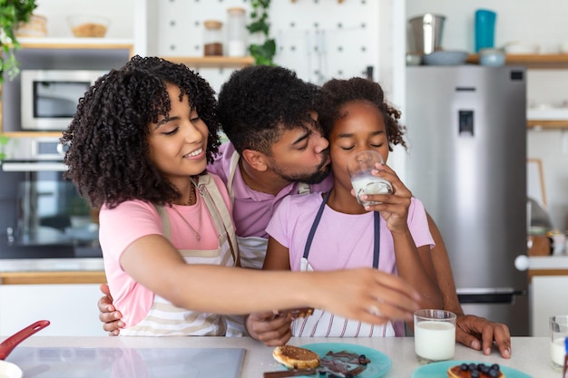 Família feliz tomando café da manhã na cozinha Pai e filha com a mãe fazendo panquecas