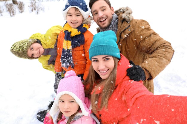 Familia feliz tomando selfie en parque nevado en vacaciones de invierno