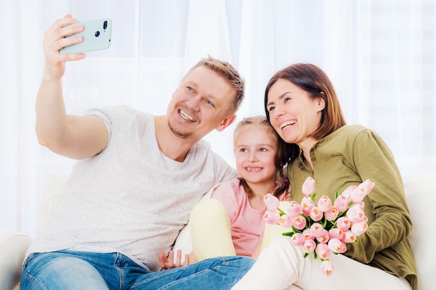 Familia feliz tomando selfie con regalos festivos en el día de la madre