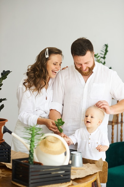 Familia feliz trabajando en casa. Trasplantar plantas con su hijo