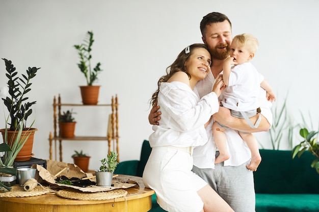 Familia feliz trabajando en casa. Trasplantar plantas con su hijo