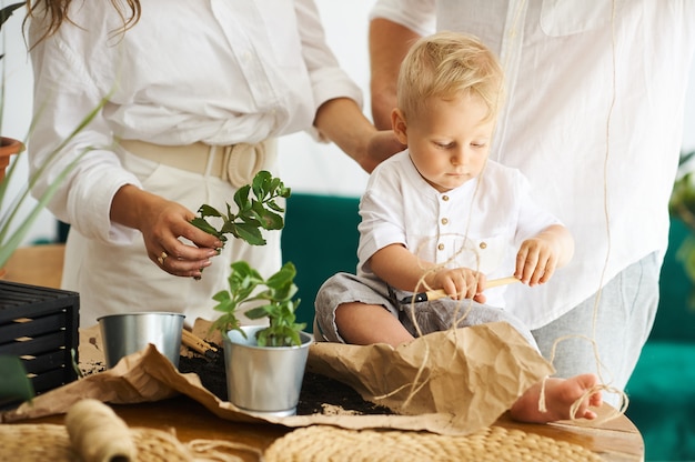 Familia feliz trabajando en casa. Trasplantar plantas con su hijo