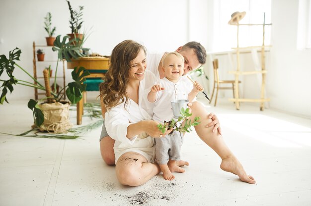 Familia feliz trabajando en casa. Trasplantar plantas con su hijo