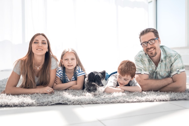 Familia feliz tumbada en la alfombra en la habitación en la nueva foto de casa con espacio para copiar