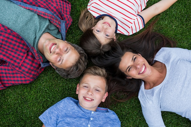 Familia feliz tumbado en la hierba en el parque en un día soleado