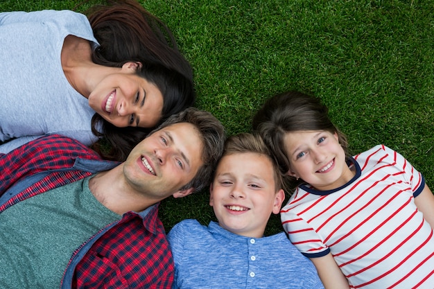 Familia feliz tumbado en la hierba en el parque en un día soleado