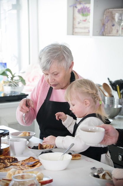 Família feliz uma garotinha e sua avó cozinhando na cozinha