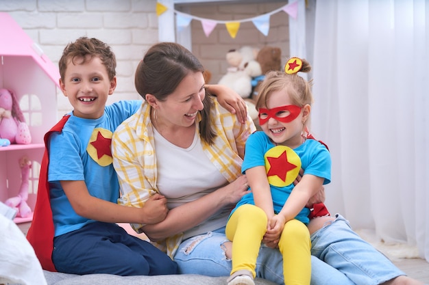 Família feliz. uma jovem brinca com seus filhos em super-heróis.