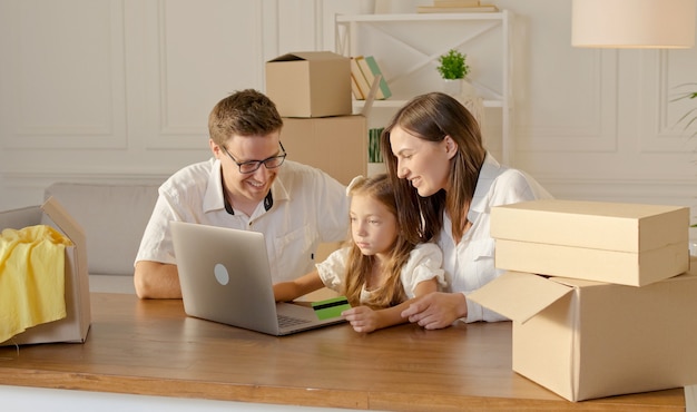 Una familia feliz usa una computadora portátil para comprar en línea sentado en casa