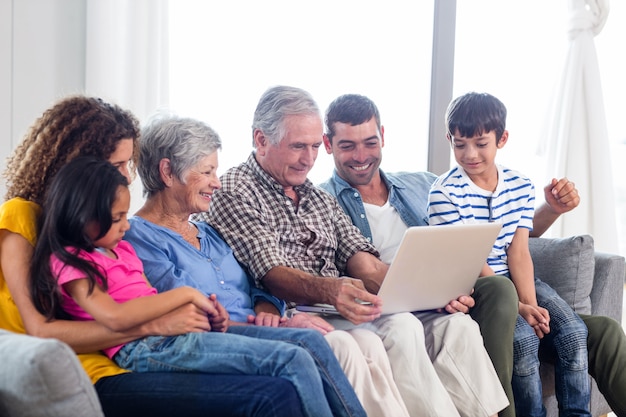 Familia feliz usando la computadora portátil en el sofá