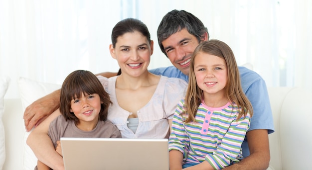 Familia feliz usando una computadora portátil en el sofá