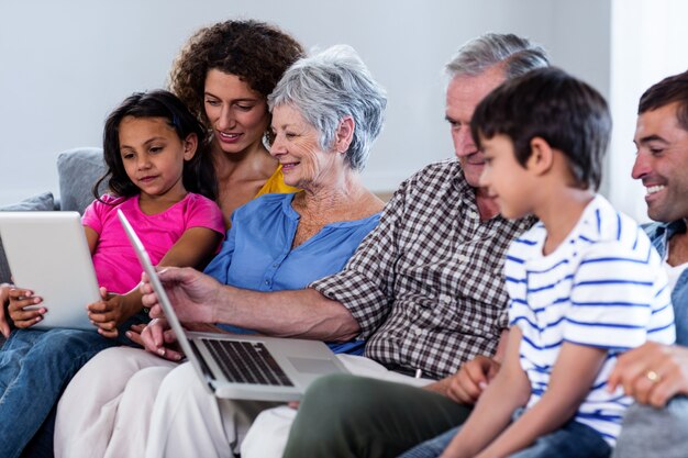 Foto família feliz usando laptop e tablet digital na sala de estar