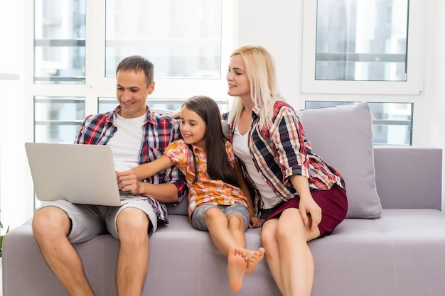 Familia feliz usando una laptop juntos en un sofá en casa