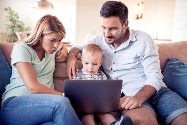 Foto familia feliz usando una laptop juntos en un sofá en casa