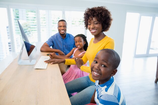 Família feliz usando o computador na sala de estar em casa