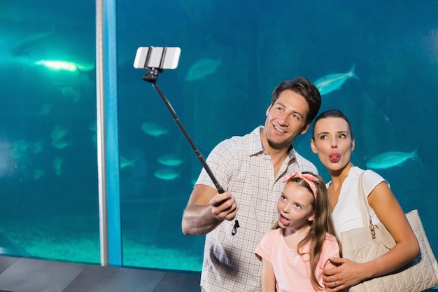 Família feliz usando stick selfie