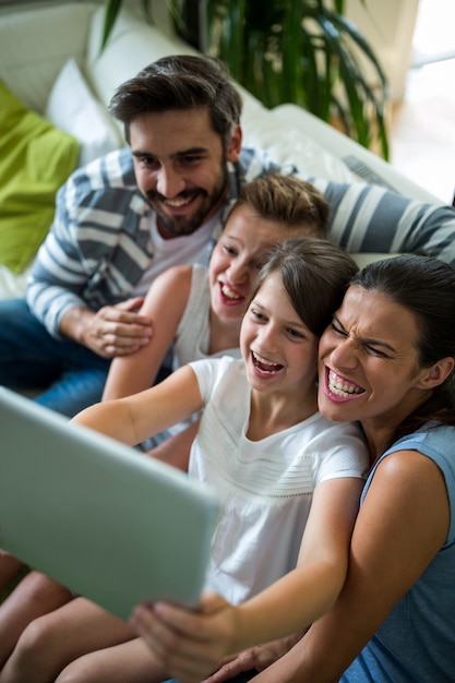 Família feliz usando tablet digital na sala de estar