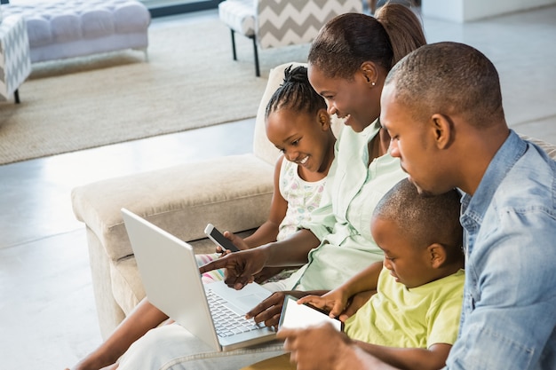 Família feliz usando tecnologia juntos na sala de estar
