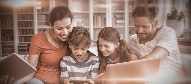 Foto familia feliz usando tecnologías mientras está sentado en el sofá