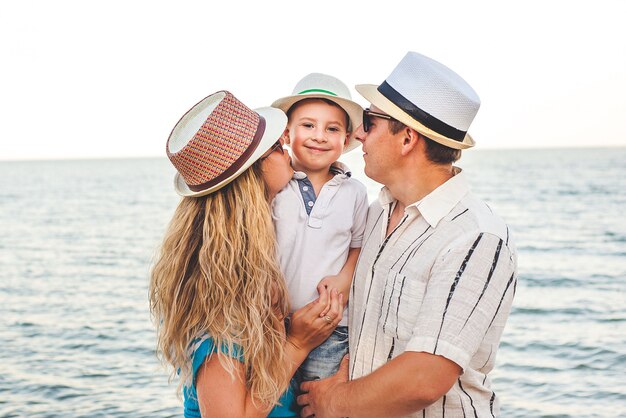 Foto familia feliz de vacaciones. mamá, papá y su pequeño hijo están parados en la playa.