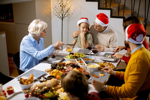 Familia feliz de varias generaciones celebrando el año nuevo junto a la mesa en casa