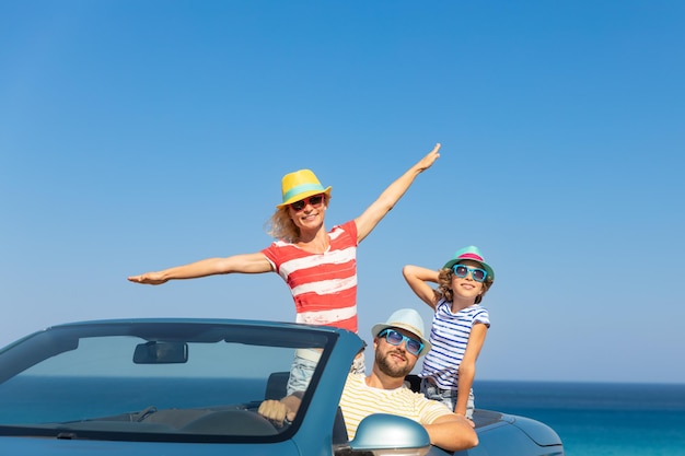 Família feliz viaja de carro no mar Mãe pai e filha se divertindo no conceito de férias de verão cabriolet azul