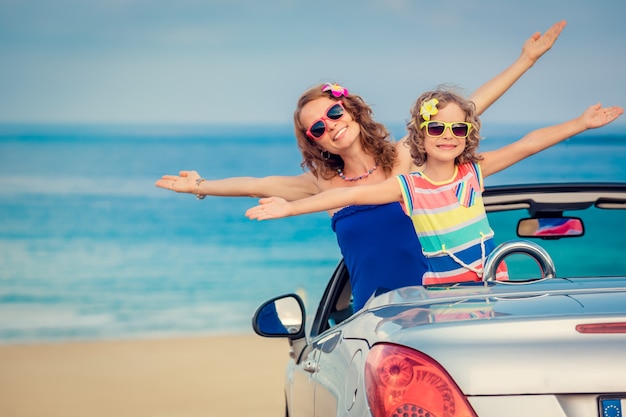 Família feliz viaja de carro para o mar Mulher e criança se divertindo no cabriolet Conceito de férias de verão