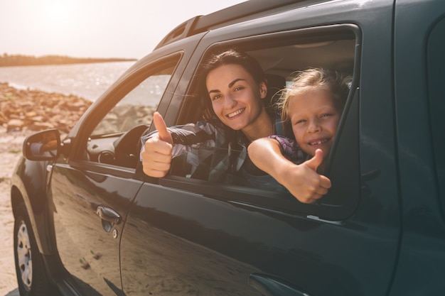 Familia feliz en un viaje por carretera en su coche. Papá, mamá e hija viajan por el mar, el océano o el río. Paseo de verano en automóvil