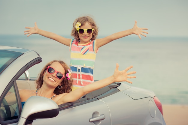 Familia feliz viaje en coche al mar Mujer y niño divirtiéndose en cabriolet Concepto de vacaciones de verano