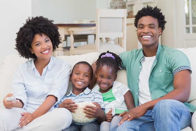 Familia feliz viendo la televisión comiendo palomitas de maíz