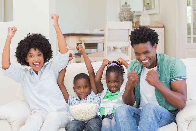 Familia feliz viendo televisión comiendo palomitas de maíz