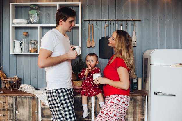 Familia feliz vistiendo pijamas de Navidad cocinar junto con su pequeña hija.