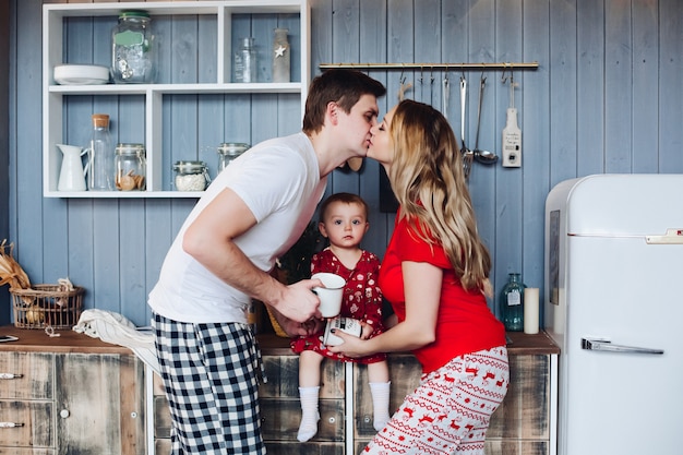 Familia feliz vistiendo pijamas de Navidad cocinar junto con su pequeña hija.