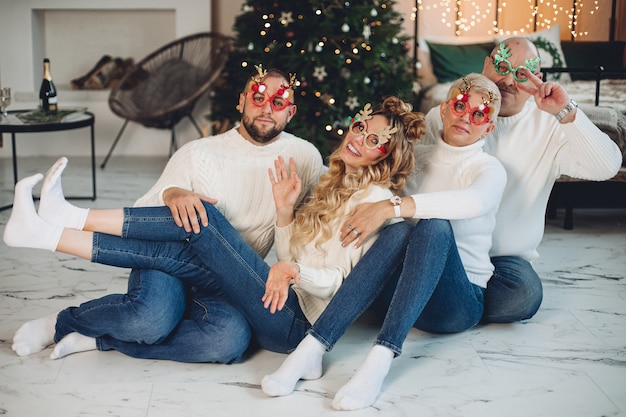 Familia feliz vistiendo suéteres blancos y divirtiéndose mientras celebramos el año nuevo juntos