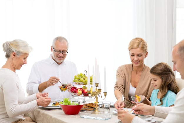 família, feriados, geração e conceito de pessoas - família sorridente jantando em casa