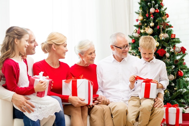 família, feriados, geração, natal e conceito de pessoas - família sorridente com caixas de presente sentadas no sofá em casa