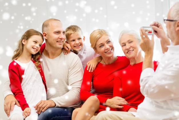 família, feriados, geração, natal e conceito de pessoas - família sorridente com câmera fotografando e sentado no sofá em casa
