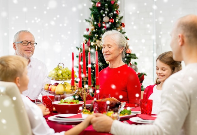 família, feriados, geração, natal e conceito de pessoas - família sorridente jantando e rezando em casa